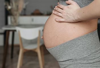 Grávida com a mão na barriga vestindo roupa de ginástica. Foto de Pavel Danilyuk