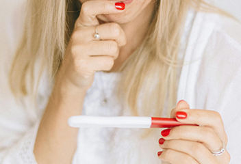 Foto com mulher segurando um teste de gravidez. Foto por Nataliya Vaitkevich